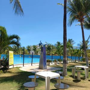 un parque con mesas, palmeras y una piscina en Apartamento Aluguel Morro Branco., en Beberibe