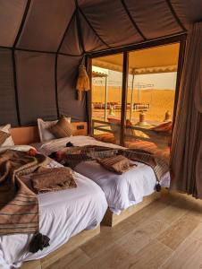 1 dormitorio con 2 camas en una tienda de campaña en Merzouga Dunes Luxury Camps, en Merzouga