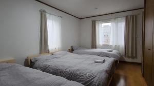 two beds in a room with a window at SecondHouse Otaru Garden in Otaru
