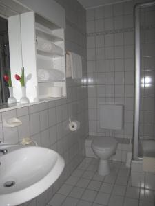 a white bathroom with a sink and a toilet at Zum Flößer in Neckartenzlingen
