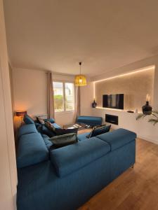 a living room with a blue couch and a tv at LoveRoom La Parenthèse Secrète in Lampaul-Plouarzel