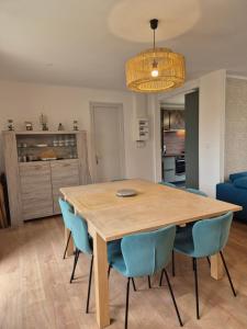 uma sala de jantar com uma mesa de madeira e cadeiras azuis em petite maison chaleureuse du GR34 em Lampaul-Plouarzel