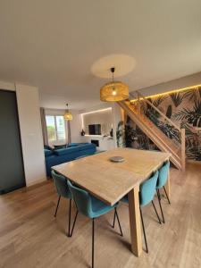 uma sala de jantar com uma mesa de madeira e cadeiras azuis em petite maison chaleureuse du GR34 em Lampaul-Plouarzel