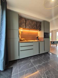 a kitchen with green cabinets and a tile floor at LoveRoom La Parenthèse Secrète in Lampaul-Plouarzel