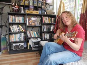 Una donna seduta su un divano che suona la chitarra di Harvest Moon Guest House a Pokhara