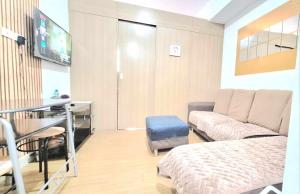 a room with a bed and a desk and a television at Snuggle and Comfy 1BR with WiFi in Grace Residences Taguig City in Manila