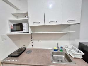 a kitchen with a sink and a microwave at Snuggle and Comfy 1BR with WiFi in Grace Residences Taguig City in Manila