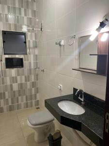 a bathroom with a sink and a toilet and a mirror at Casa Bela Vista in São Roque de Minas