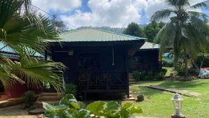 ein schwarzes Haus mit einem grünen Dach und Palmen in der Unterkunft Nazri's Place 2 in Tioman Island