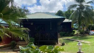 una casa negra con techo verde y palmeras en Nazri's Place 2, en Tioman Island