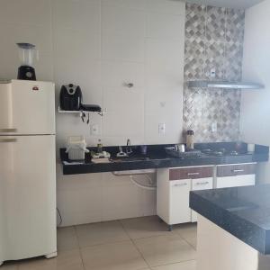 cocina con armarios blancos y nevera blanca en Casa Bela Vista en São Roque de Minas