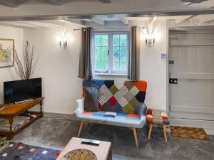 a living room with a couch and a tv at Raspberry Cottage in Great Mongeham