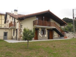 ein Haus mit einem Balkon und einem Baum im Hof in der Unterkunft Apartamentos Aldagaia in Hernani