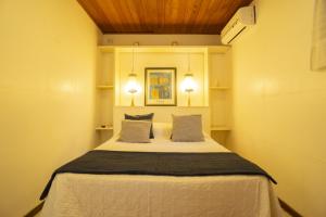 a bedroom with a bed with two pillows and two lights at Regina Apartments in Morro de São Paulo