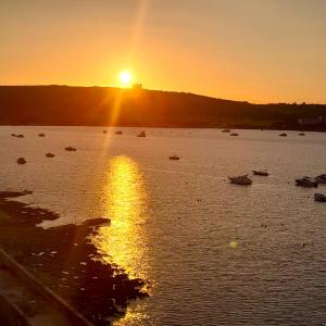 a sunset over a large body of water with boats at Seafront Maisonette Ocean Views & Terrace in Mellieħa