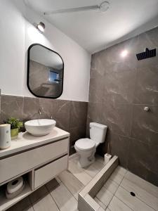 a bathroom with a toilet and a sink and a mirror at Linda casa de 2 pisos, con cochera cerca de PIMENTEL in Chiclayo