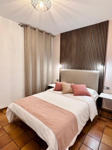 1 dormitorio con 1 cama blanca grande con almohadas rosas en Cozy Up Spain en Valencia