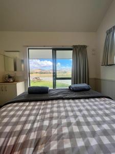 a bedroom with a large bed with a large window at Gold Miners Cottage in Tarras