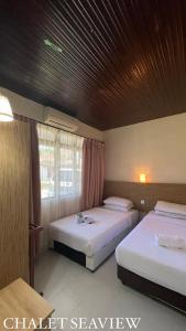 a bedroom with two beds and a window at Lovita Tanjung Bidara Beach Resort in Melaka