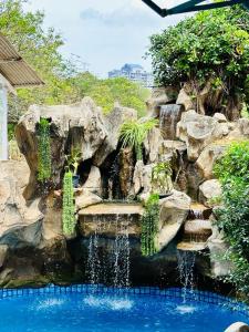 a waterfall in a garden with rocks and plants at Green Villa Grandeur at A Famosa Resort Melaka in Kampong Alor Gajah