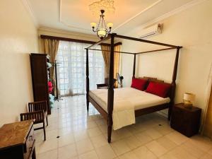 a bedroom with a canopy bed with red pillows at Green Villa Grandeur at A Famosa Resort Melaka in Kampong Alor Gajah