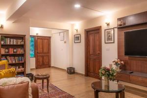 een woonkamer met een flatscreen-tv en een bank bij Jais Cottage A Charming Hideaway in Shimla