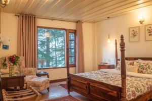 a bedroom with a bed and a chair and a window at Jais Cottage A Charming Hideaway in Shimla +5 photos