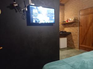 una televisione appesa a un muro in una camera da letto di Chácara das flores a Gonçalves