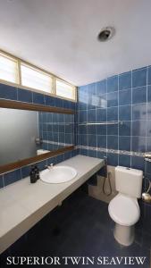 Baño de azulejos azules con aseo y lavamanos en Lovita Tanjung Bidara Beach Resort en Melaka