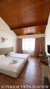 a bedroom with two beds and a wooden ceiling at Lovita Tanjung Bidara Beach Resort in Malacca