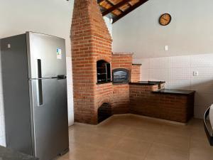 La cocina está equipada con horno de ladrillo y nevera. en Chacara em Socorro- SP próx ao centro, com piscina e area gourmet, en Socorro