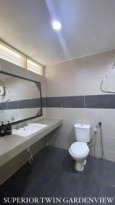 a bathroom with a toilet and a sink and a mirror at Lovita Tanjung Bidara Beach Resort in Melaka