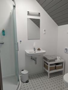 a white bathroom with a sink and a shower at ZánKapu Szálláshely in Zánka