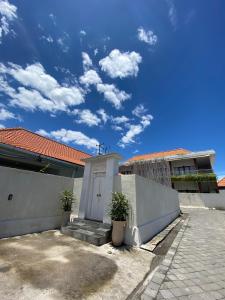 une maison avec une clôture blanche et une porte blanche dans l'établissement The Jangkar Canggu Guesthouse & Villa, à Canggu