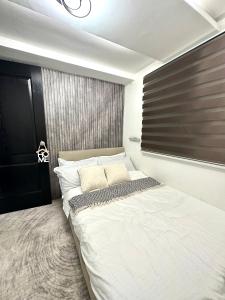 a bedroom with a large white bed with a black headboard at Sunshine Cabin in General Santos