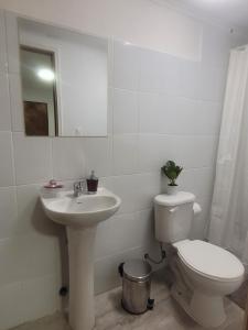 a white bathroom with a toilet and a sink at C&C TALTAL in Taltal