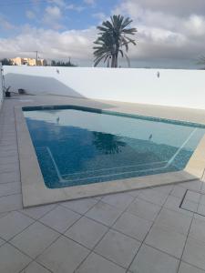 a swimming pool next to a white wall at Dar Midoun Villa with pool in center city in Midoun