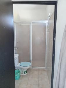 a bathroom with a toilet and a glass shower door at Casa Alegre Yucatan in Kanasín