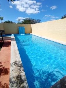 a swimming pool with blue water in front of a wall at Casa Alegre Yucatan in Kanasín