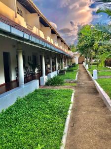 a building with a pathway next to some grass and palm trees at Green Island Nature lodge and Villa in Kammala South