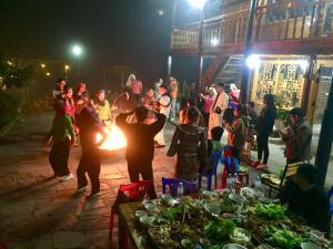 um grupo de pessoas em pé em torno de uma fogueira à noite em Fan Lap Homestay em Sapa