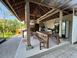 un pabellón con una mesa y bancos en un patio en Canggu Nadi 2 Guest House, en Canggu