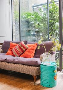 - un canapé violet avec des oreillers orange dans le salon dans l'établissement Beautiful Mews House - Notting Hill (pbm), à Londres