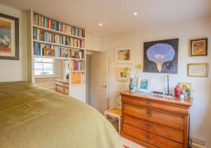 sypialnia z łóżkiem, komodą i półkami na książki w obiekcie Beautiful Mews House - Notting Hill (pbm) w Londynie