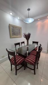 a dining room with a glass table and chairs at Apartamento Praia Barra da Tijuca -Acolhedor e Confortável in Rio de Janeiro