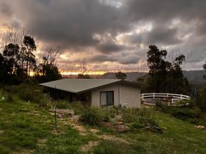 a small house in a field under a cloudy sky at Mountain Tranquility in Mount Tomah