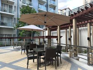 um pátio com mesas e cadeiras e um guarda-sol em One Palm Tree villas with free parking em Manila
