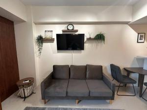 a living room with a couch and a clock on a wall at One Palm Tree villas with free parking in Manila