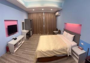 a bedroom with a bed and a flat screen tv at 溫沙堡汽車旅館 Windsor Castle Garden Motel in Jiaoxi
