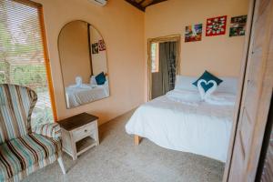 1 dormitorio con cama, silla y espejo en Ravelyn House en Silebeng